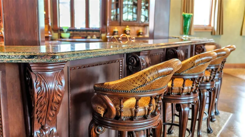 Genuine Crocodile Hide adorns the strikingly detailed Hardwood Barstools at the wood engraved Breakfast Bar.