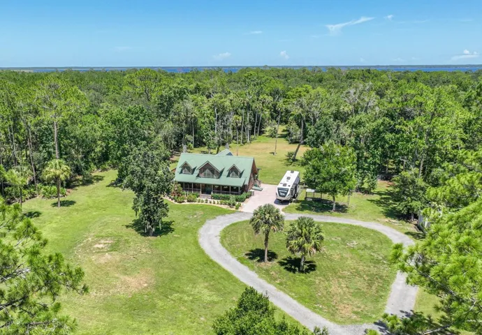 Elevated aerial captures the log home surrounded by five private acres.