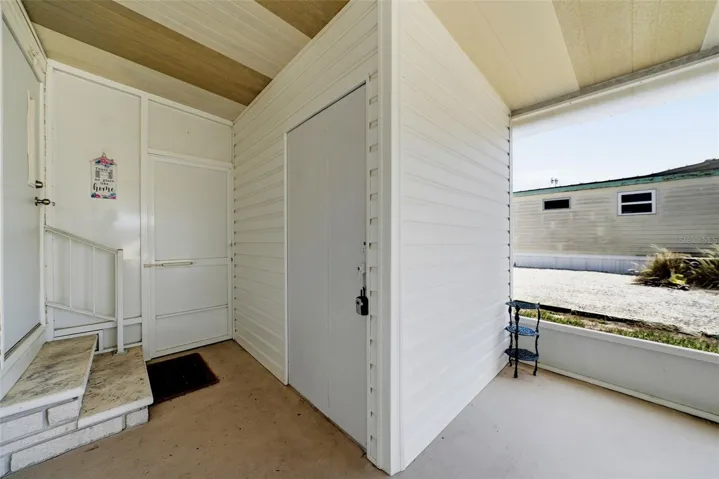 carport lanai looking at workshop (with lock box on it) and door to the laundry room