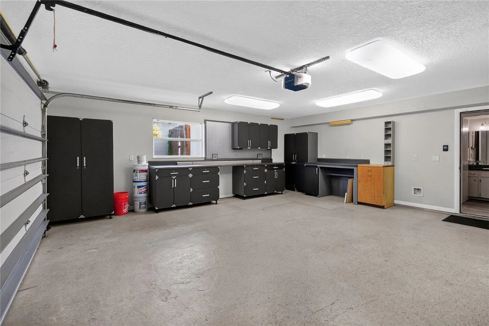 View 3 - Garage w/ cabinetry, shelving strategically placed electrical outlets throughout w/ WORKSHOP lighting. - showing EASE of access to hallway for 1/2 bath.