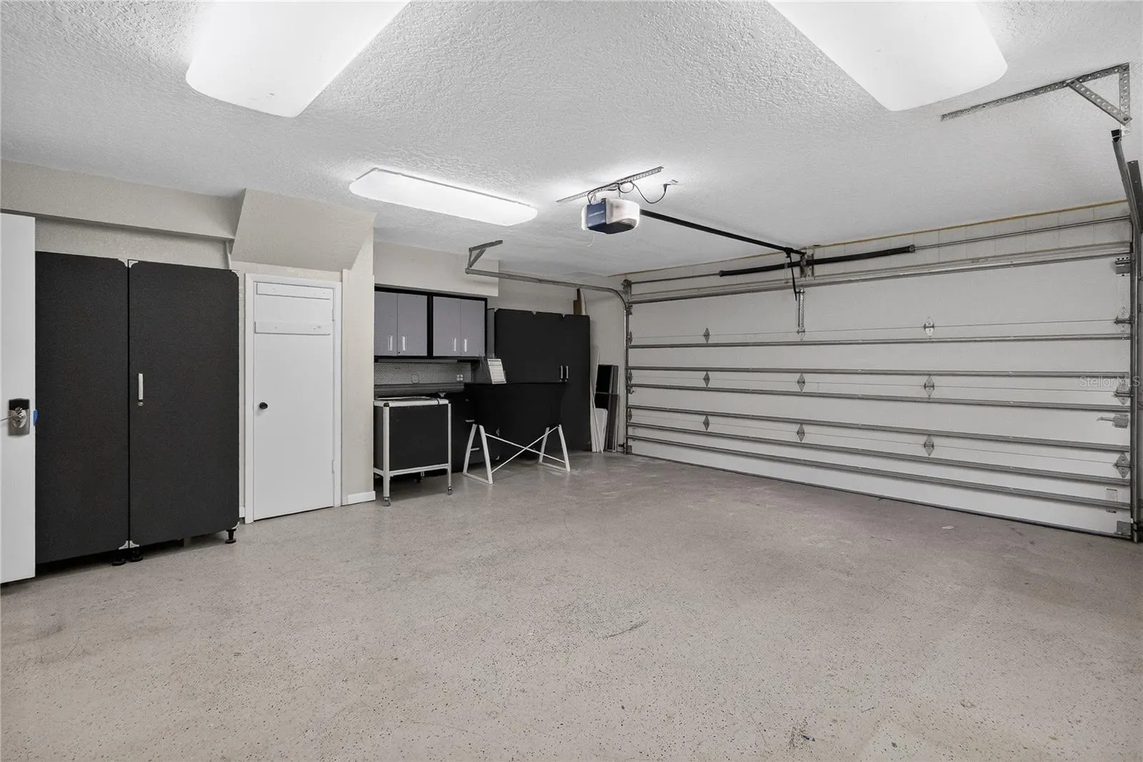 View 2 -Garage w/ cabinetry, shelving strategically placed electrical outlets throughout w/ WORKSHOP lighting.