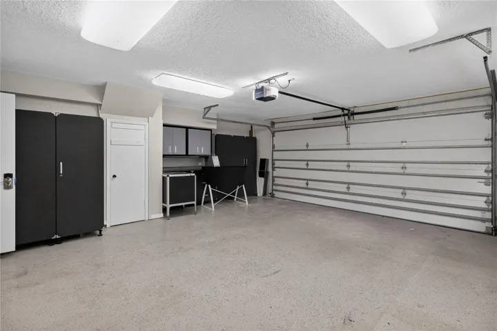 View 2 -Garage w/ cabinetry, shelving strategically placed electrical outlets throughout w/ WORKSHOP lighting.