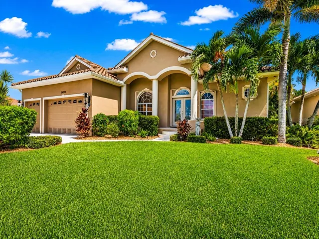 Beautiful tropical curb appeal with elegant architectural details, manicured landscaping and a stately double-door entry.