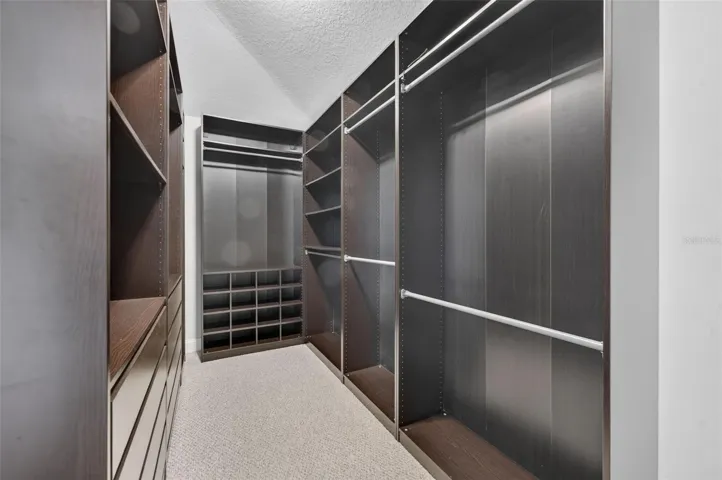 Custom floor to ceiling built-ins, offering generous hanging space, shelving, drawers, and dedicated shoe storage.
