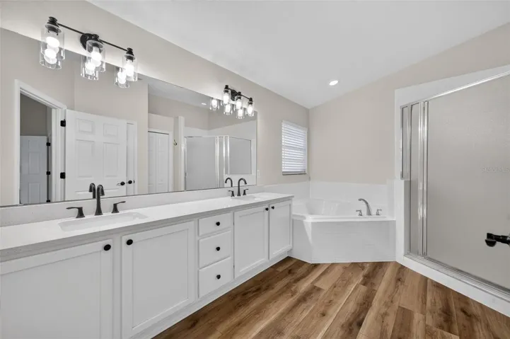 Unwind in the primary bathroom featuring dual sinks, a relaxing tub, and a spacious walk-in shower.
