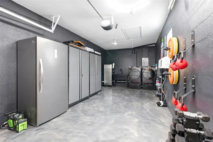 Immaculate garage with a finished epoxy floor, A/C unit, double utility sink, and pull down attic stairs