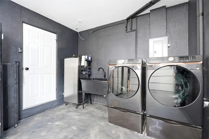 Immaculate garage with a finished epoxy floor, A/C unit, double utility sink, and pull down attic stairs