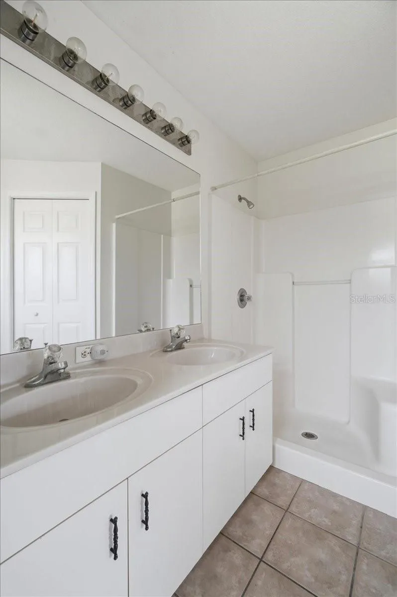 Spacious ensuite primary bathroom featuring a double vanity with his and hers sinks.