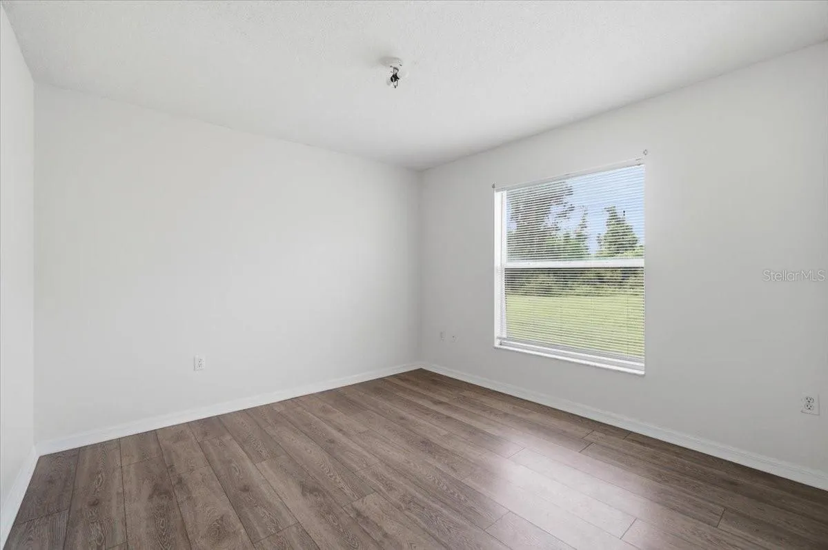 Second spacious bedroom with ample natural light, comfortably accommodating a queen-sized bed and additional furniture.
