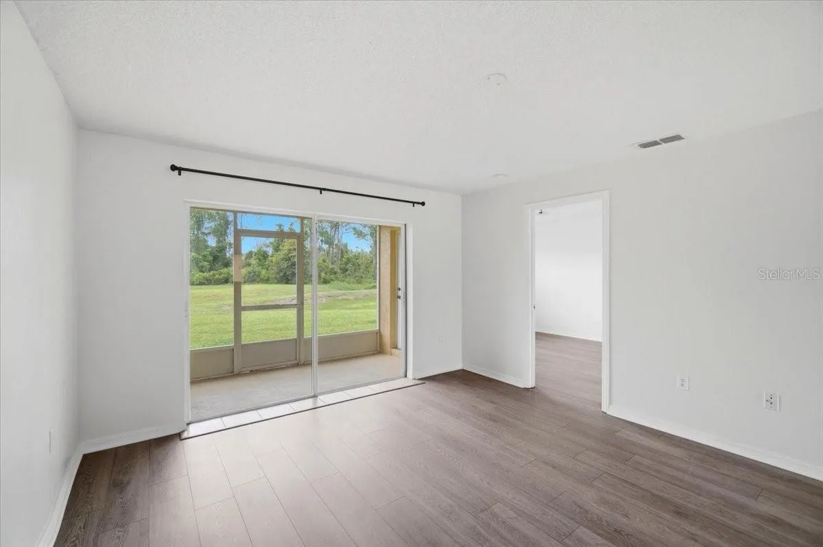 Bright and inviting living room featuring an open-concept layout that flows seamlessly onto an enclosed back porch, perfect for year-round entertaining. This space offers complete privacy with no rear neighbors, allowing you to enjoy peaceful, unobstructed views from the comfort of your home.