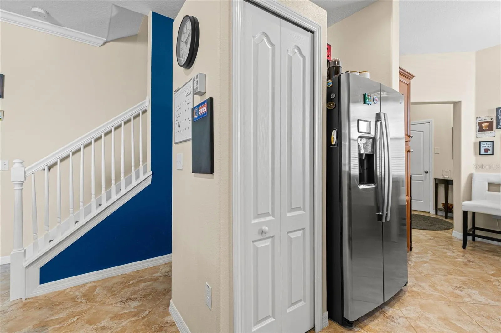 The kitchen sits just steps from the staircase, with the pantry tucked beside the refrigerator and easy access to the home’s main living spaces.