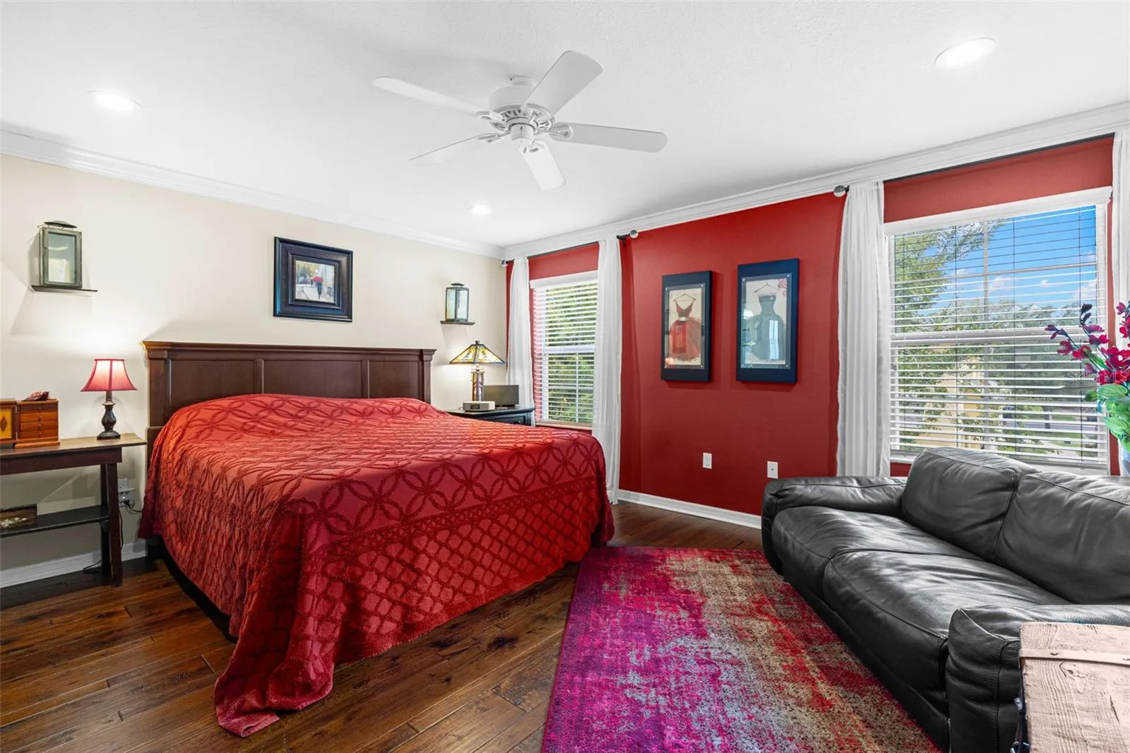 The spacious primary bedroom offers hardwood flooring, a ceiling fan and room for a sitting area, with three windows bringing in plenty of natural light.