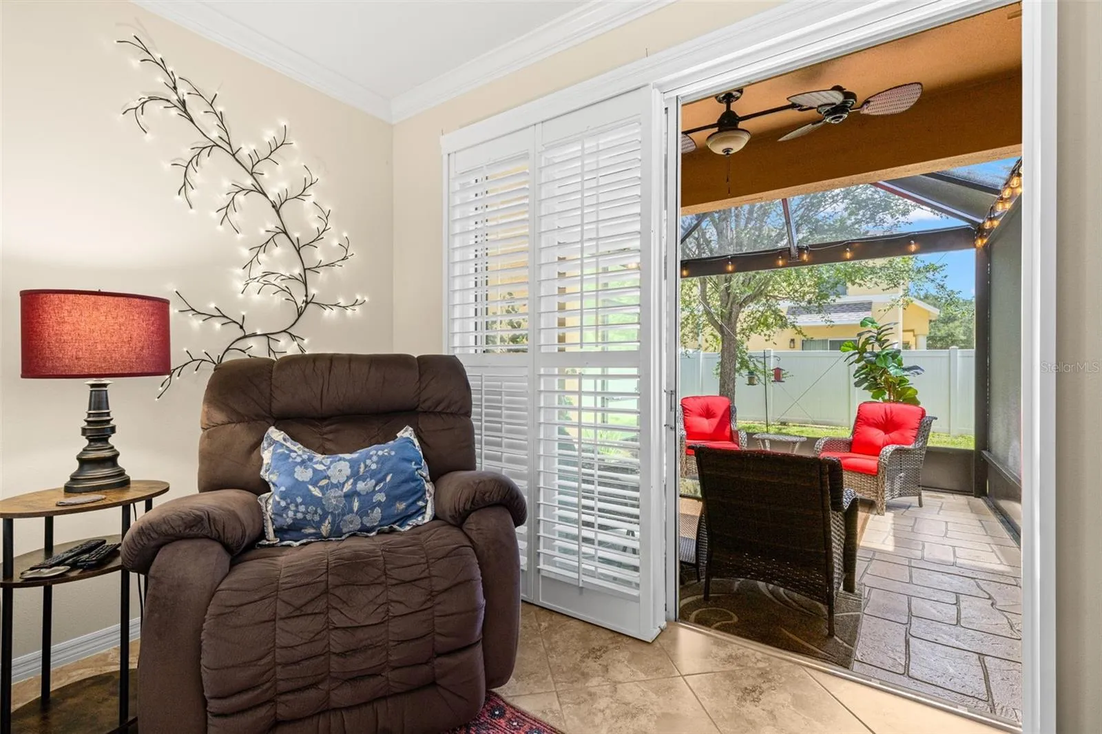 Plantation shutters frame the doors to the new screened lanai, creating an easy extension of the living room with stamped concrete flooring and a ceiling fan.