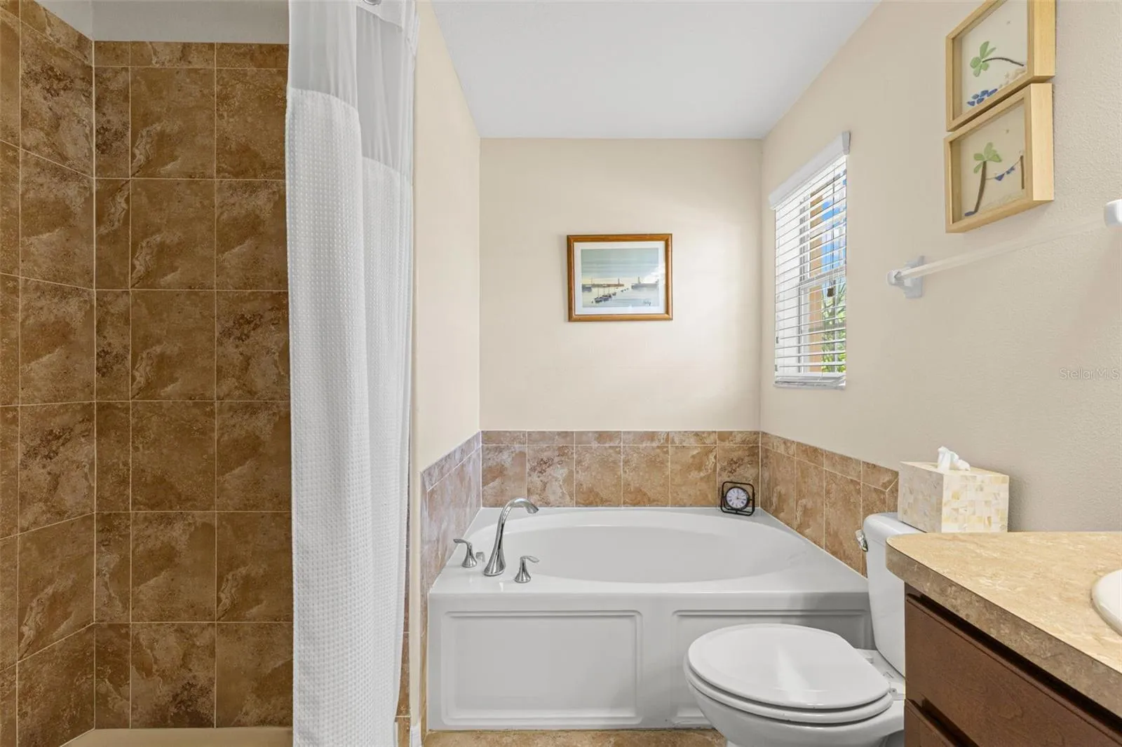 A deep soaking tub sits beside the separate tiled shower, with a window bringing natural light into the primary bath.