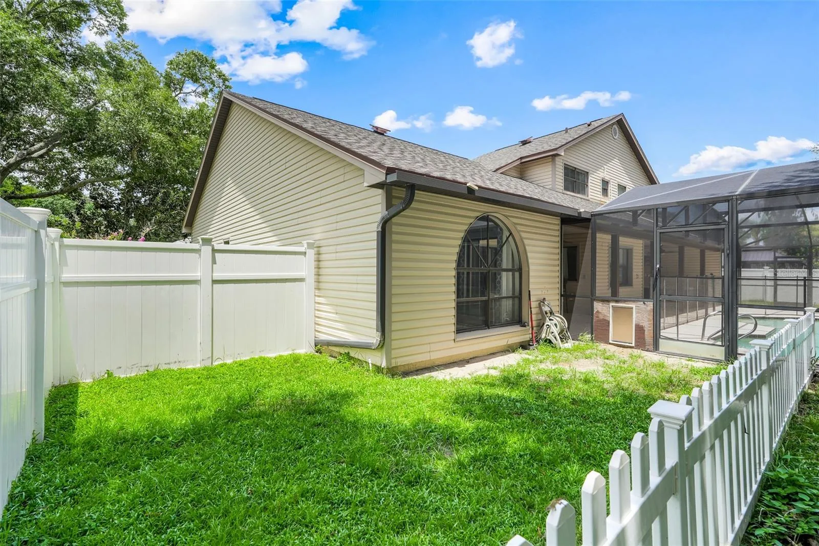 Small fenced in area inside the yard with a doggie door coming from pool area