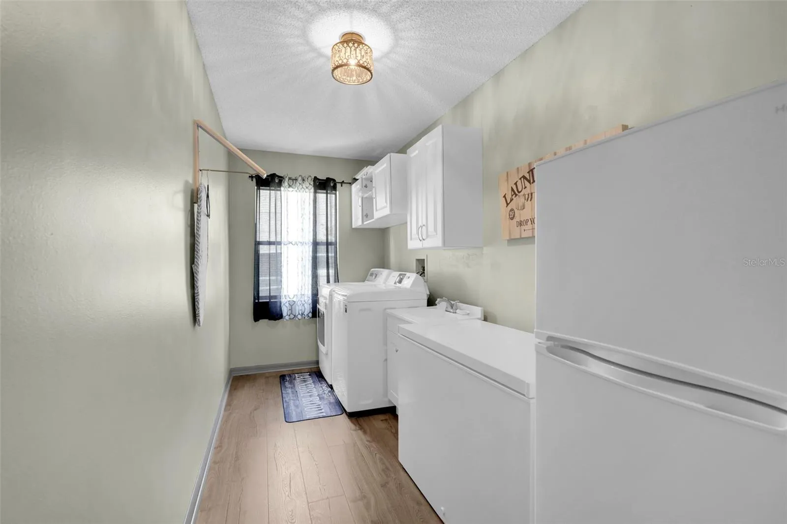 Large downstairs laundry room with cabinets for storage and refrigerator & freezer that convey