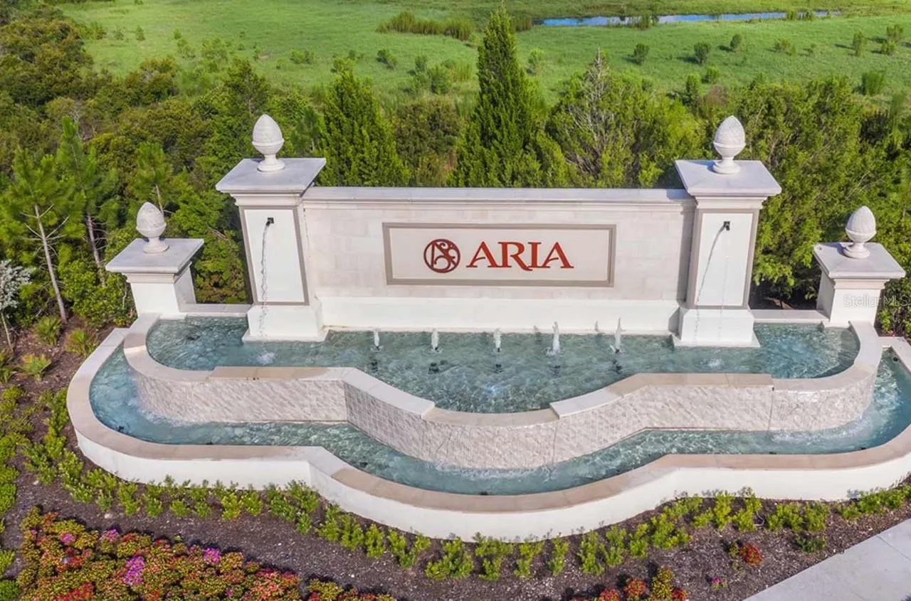 A stacked-stone entry monument bearing the Aria name is framed by dual cascading fountains and manicured landscaping, marking the community's presence from the road. It's the first impression of the resort-style lifestyle found throughout the neighborhood.