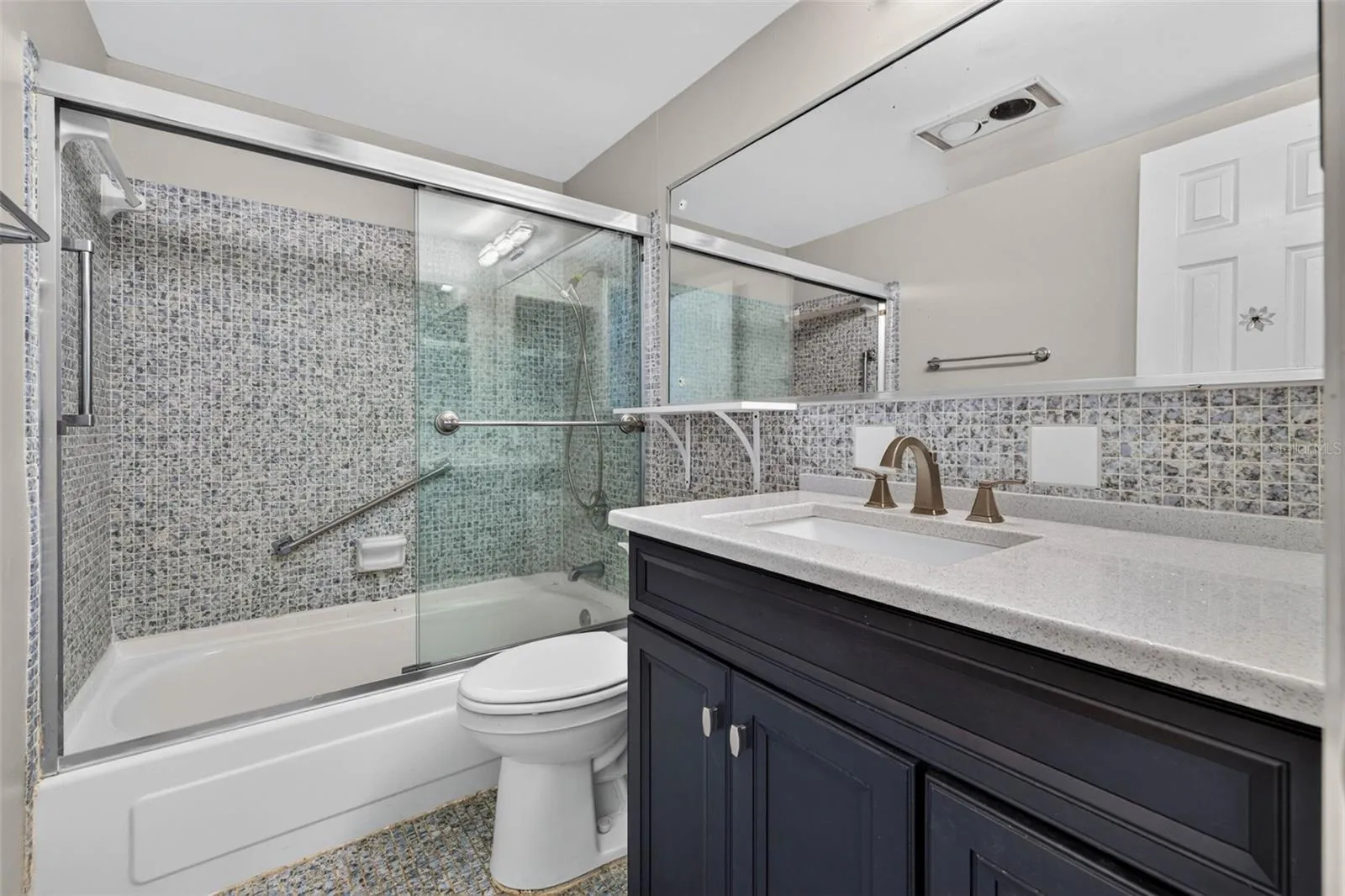 Modern full bath with a updated vanity, glass shower doors, and elegant tile finishes.