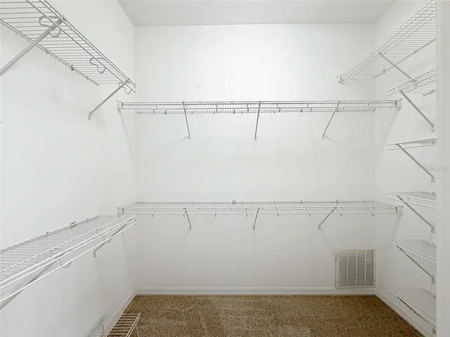 Large Walk in closet with racks and new carpet.