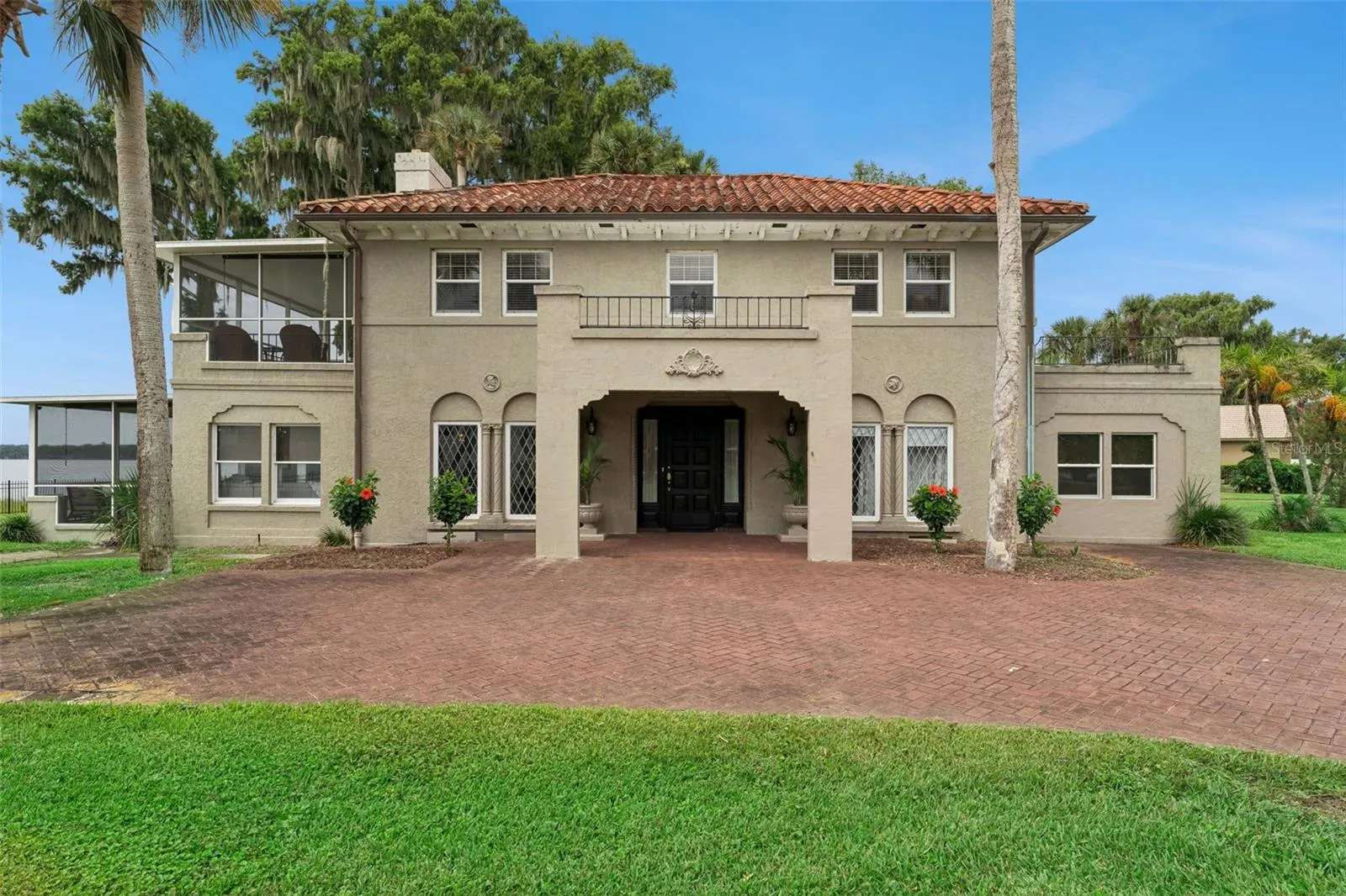Stately two-story facade with arched entry, wrought iron balconies, and leaded glass windows
