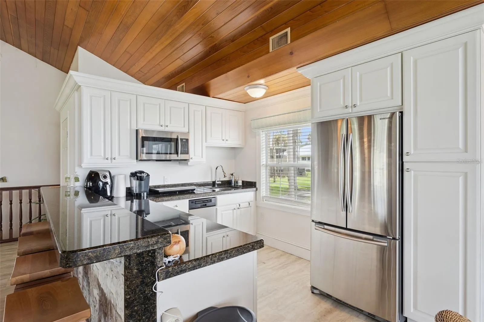 Secondary prep kitchen with crisp white cabinetry, granite counters, and garden window