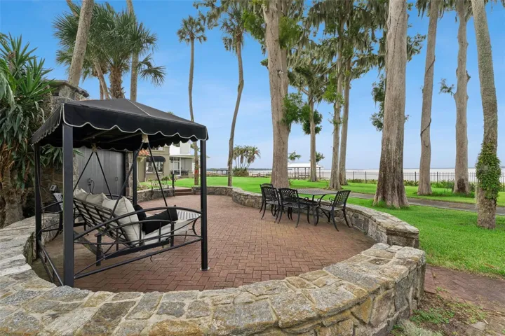 Park-like rear grounds with mature palms, manicured lawn, and lakefront porch