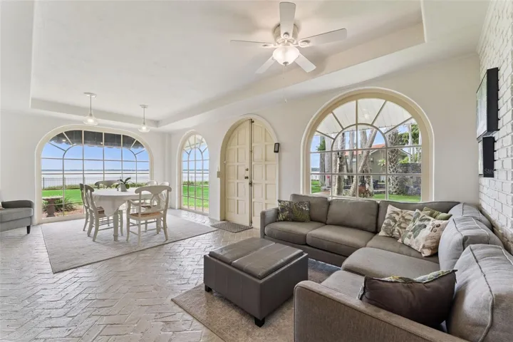 Casual dining with floor-to-ceiling arched windows framing the waterfront lawn