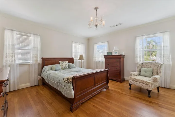 Elegant guest bedroom with chandelier and hardwood floors