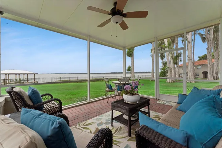 Screened lanai with ceiling fan, overlooking the lush lawn and Lake Harris