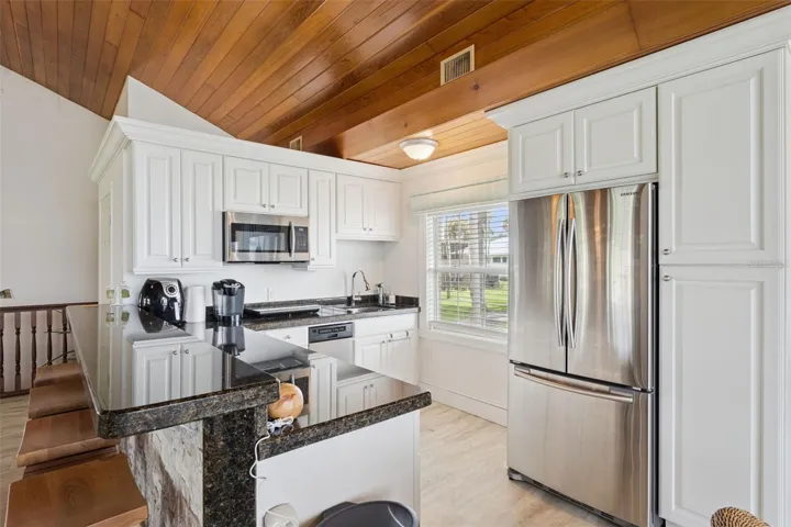 Secondary prep kitchen with crisp white cabinetry, granite counters, and garden window