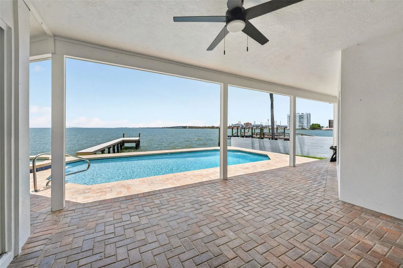 Covered back patio with stunning views of the pool and Tampa Bay, perfect for enjoying the outdoors in comfort.