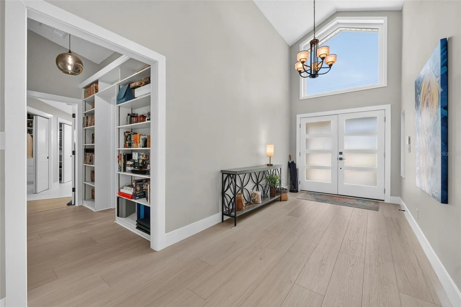 Bright and welcoming entryway featuring a large window above the double doors and a modern light fixture that enhances the natural light.