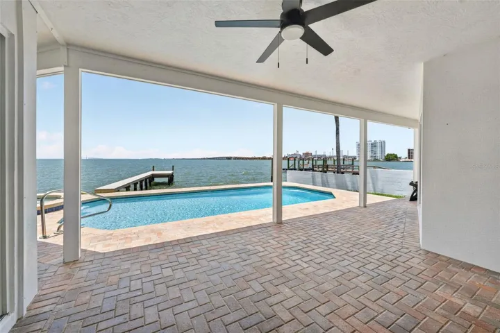 Covered back patio with stunning views of the pool and Tampa Bay, perfect for enjoying the outdoors in comfort.