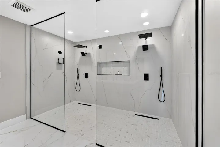 Oversized walk-in shower with seamless glass enclosure creating a spa-like experience