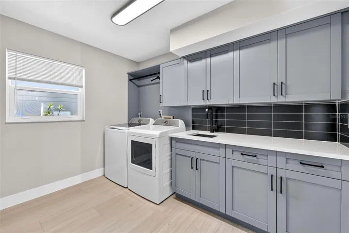 Spacious new laundry suite with utility sink, washer and dryer, and abundant built-in storage