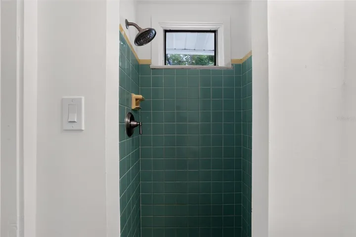 Green tile shower in the second bathroom of this 1922 bungalow