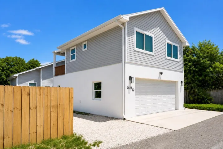 Exterior alley entrance of garage apartment: 2 tandem parking spaces on gravel.