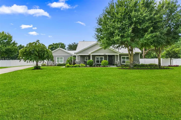 Stunning custom contemporary estate situated on over an acre, featuring exceptional curb appeal, a 30-year Galvalume metal roof, lush landscaping, and an inviting covered front porch.