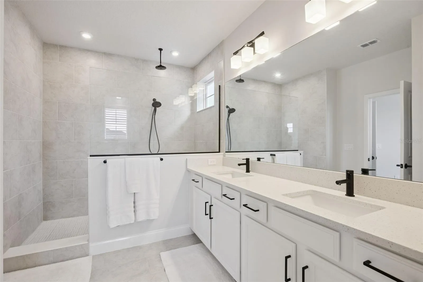 The Spa-Inspired Owner's Bath features an oversized Frameless Glass Super Shower with a Matte Black Rain Showerhead, Handheld Shower Wand and coordinating Designer Fixtues.