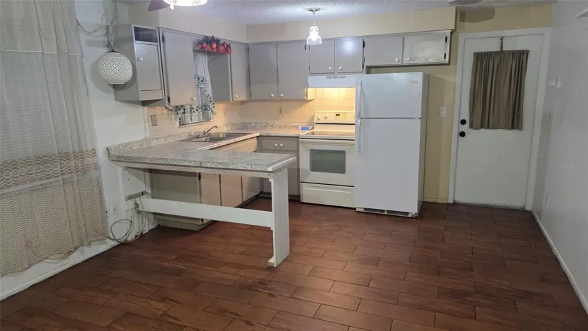 Kitchen view from the living room.  Tile flooring and ceiling fan.