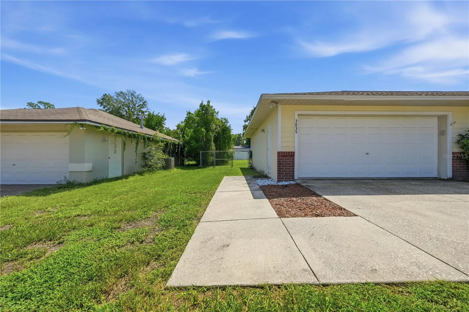 Walkway to side garage door and fenced backyard.