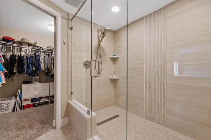 Primary updated shower with waterfall tile feature and large walk in closet
