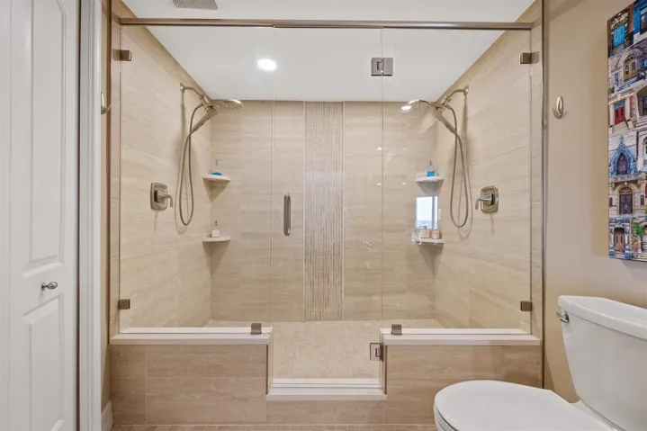Updated shower with dual shower heads and glass enclosure