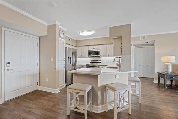 Front entry door, kitchen, breakfast bar and view of hallway with laundry closet to primary