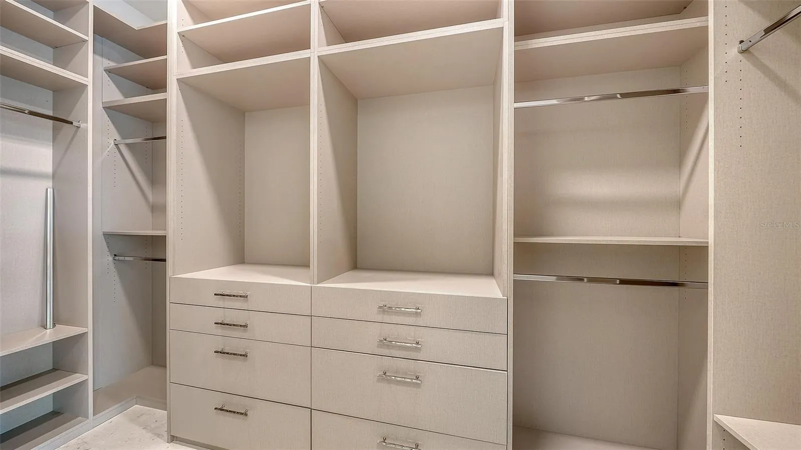 The larger of two custom walk-in closets is thoughtfully designed with extensive built-ins, abundant storage, and boutique-inspired organization for an elevated dressing experience.