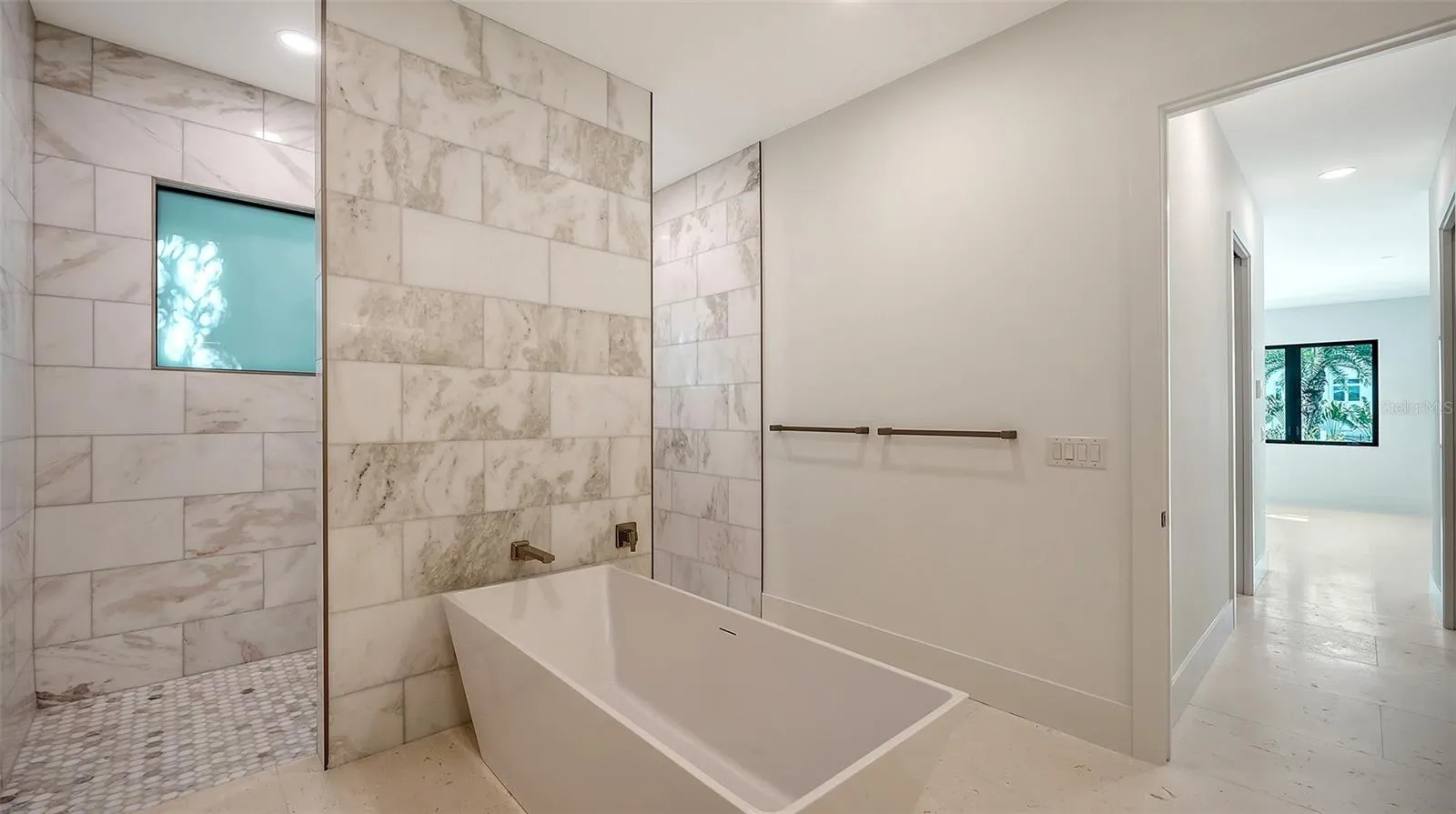 The expansive dual walk-in shower is designed for the ultimate spa experience, featuring four independently controlled shower fixtures, elegant floor-to-ceiling marble, and luxurious finishes throughout.