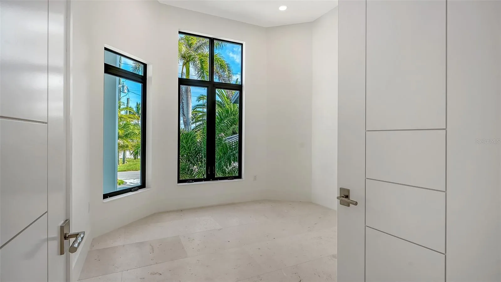 With the abundance of natural light, the private office combines floor-to-ceiling PGT impact windows with solid TruStile French doors, creating a serene, exceptionally quiet workspace with lush tropical views.