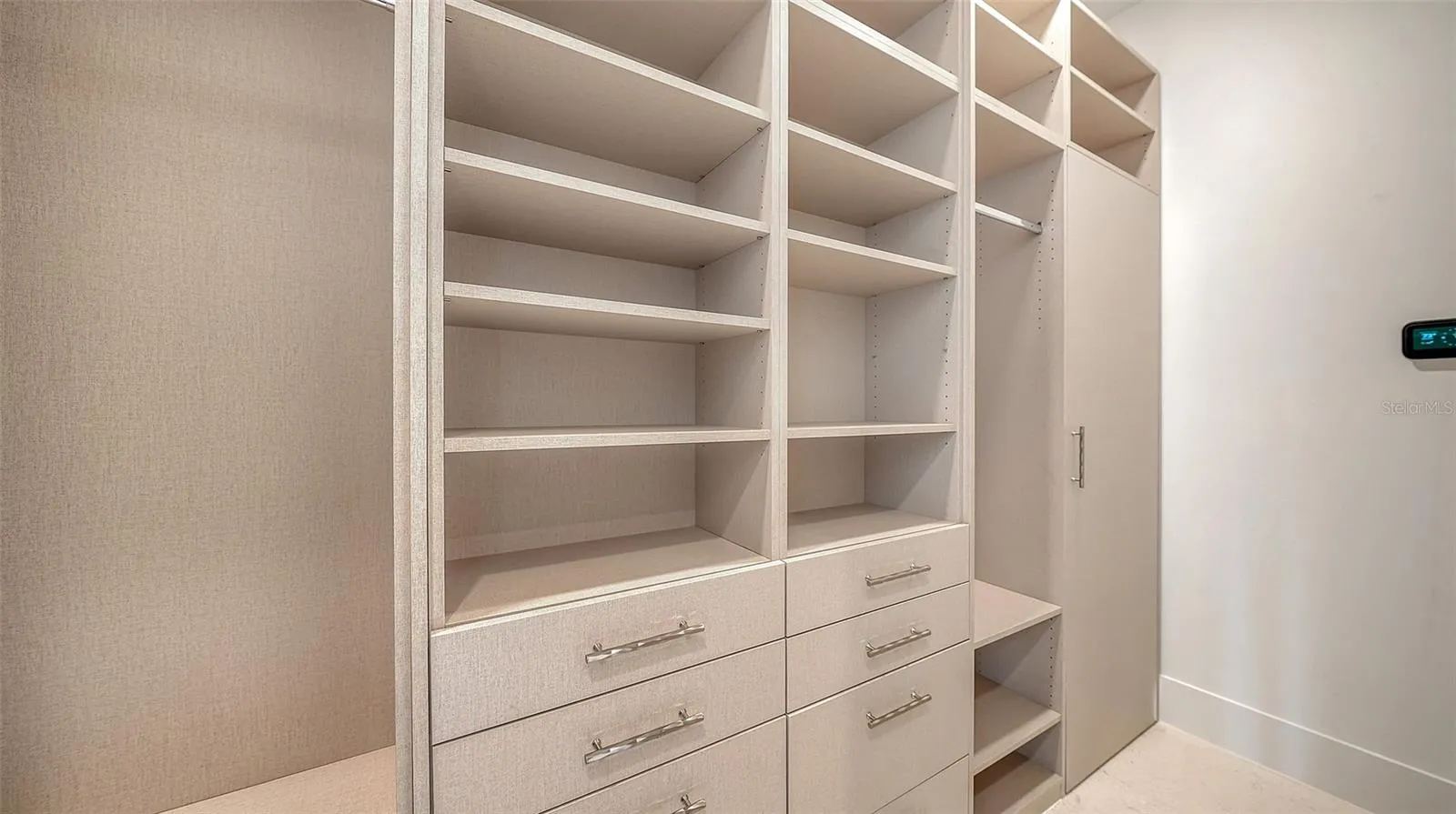 The second of two custom walk-in closets is thoughtfully appointed with extensive built-ins, generous shelving, and dedicated storage throughout.