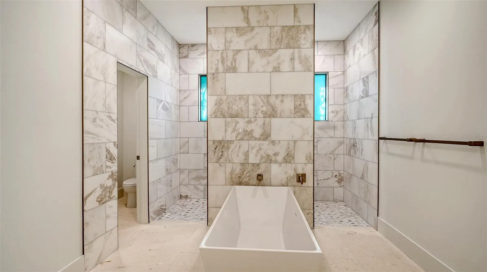 The spa-inspired primary bath is a true sanctuary, showcasing a sculptural freestanding soaking tub surrounded by stunning floor-to-ceiling marble for a serene, resort-style retreat.