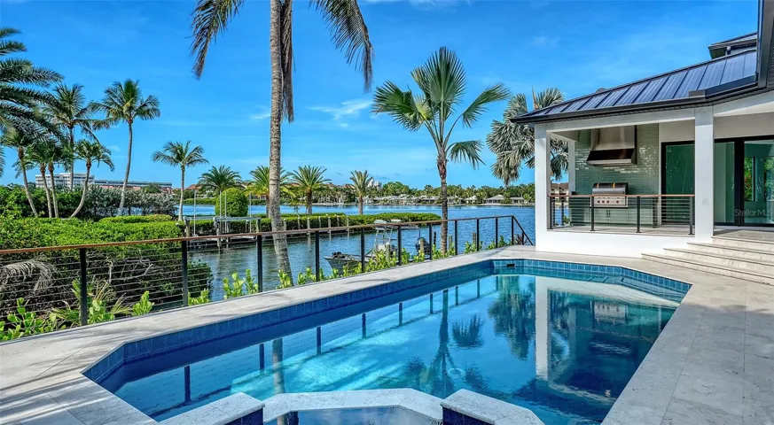 The resort-style pool and spa are the centerpiece of the outdoor living experience, perfectly positioned to capture sweeping water views while seamlessly connecting to the covered lanai, summer kitchen, and expansive waterfront terraces.